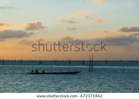 Scenery of Songkhla lake at sunset time, Silhouette people on longtail boat with fishing equipment background, Songkhla, Thailand