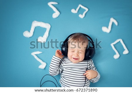 happy little boy on blue blanket background with headphones and musical notes on blue background
