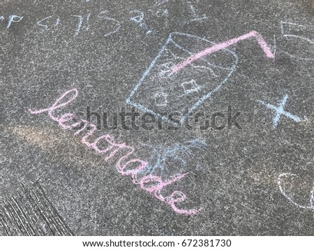 Lemonade sign on the sidewalk pointing to a kids lemonade stand