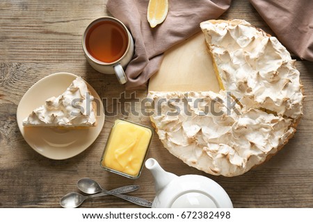 Yummy lemon meringue pie with tea on wooden table