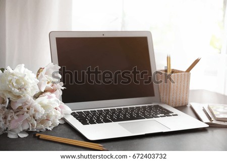 Bouquet of beautiful peony flowers, laptop and stationery on table