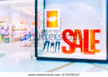 Blurred children showcases fashion boutique with clothes.Big sales on Black Friday for Christmas. Big bright red banners with the sale sign. Blurred bokeh basic background for design              
