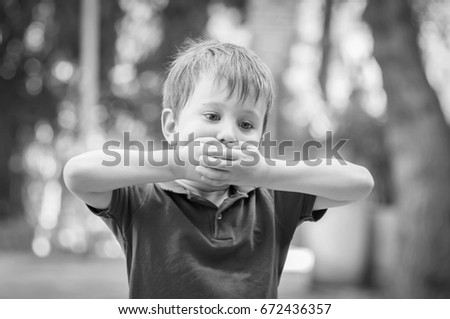 Serious little Caucasian boy closing mouth with hands. Asperger syndrome, autistic child, autism, refusal, disorder, parent abuse, school bullying, aggression, silent, refuse, psychological problem Royalty-Free Stock Photo #672436357