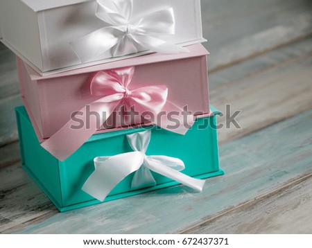 Three gift boxes, white, pink and turquoise. Top view diagonally on a wooden background.