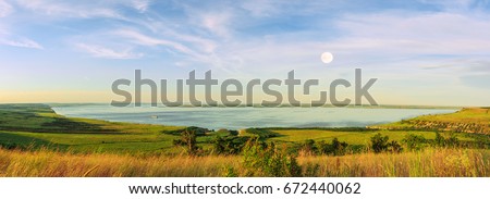 Scenic sea view from top of hills. Beautiful summer background. Amazing landscape with yellow meadows, green trees, blue sky, steep cliffs and picturesque bay. Panoramic photo. Camping, rest, relax.