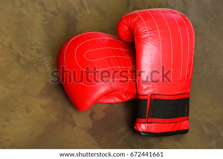 Sport equipment on dark beige background. Pair of leather boxing sportswear. Boxing gloves in red color. Training and fitness concept