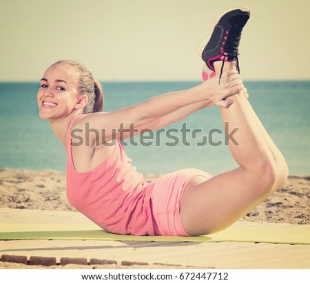 Cheerful young woman working out in beach