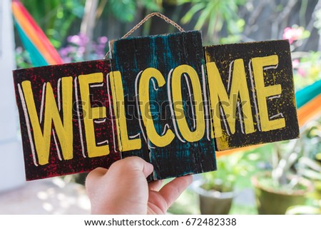 Wooden board with text welcome in man hand. Bali island. Welcome sign.