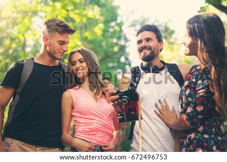 Group of friends or couples having fun with photo camera in summer park