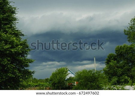 Dark sky before storm with sunlight and green nature in summer.