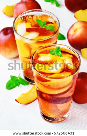 Peach ice tea in a glass with mint on a white wooden table(selective focus).