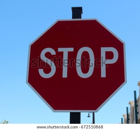 A red stop sign and the blue of the sky in the background on a close up view.