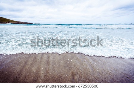 Small ocean sea waves on sandy beach in calm weather. Background landscape picture of dusk or dawn at the Atlantic ocean beach with small waves at low tide.