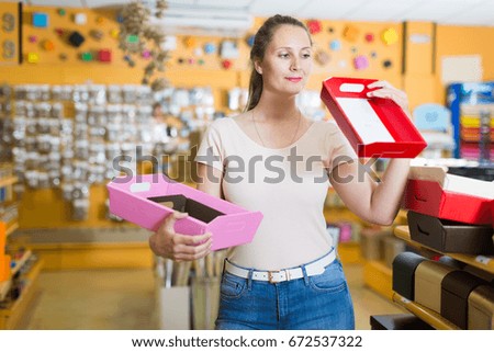 Smiling customer selects bright  boxes  for gifts in the supermarket