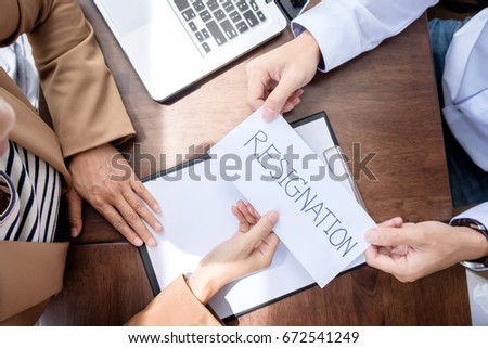 Hand of a businessman hands over a resignation letter on a wooden table to his boss.
