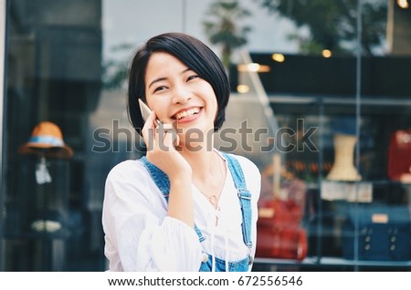 Asian woman talking on phone during shopping in front of outlet mall