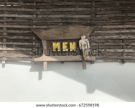 Bathroom label for men Made of wood and has a bamboo background on the concrete floor.