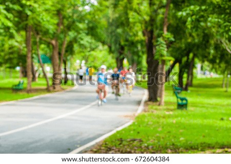 De-focus shot of people riding bicycle in public park 