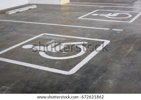 Handicap parking areas reserved for disabled people ,  White wheelchair icon on a gray asphalt parking lot