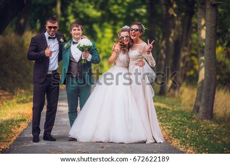 Portrait of newlywed couple having fun with bridesmaid and groomsmen in green sunny park