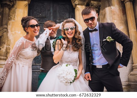 Full length portrait of newlywed couple dancing and having fun with bridesmaids and groomsmen in the city. Boys and girls in glasses.
