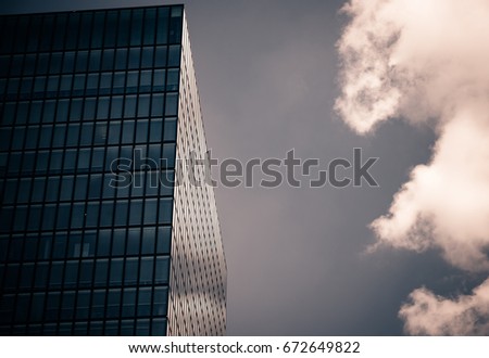 Detail of a skyscraper aginst blue sky and clouds. Retro photo.