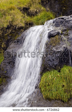 Waterfall in mountains on a background of a green grass