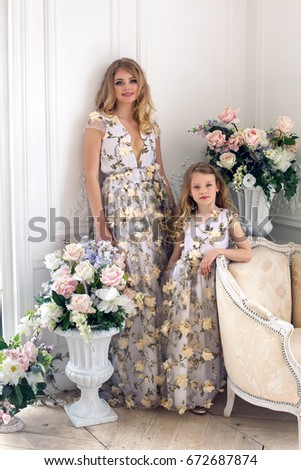 mother and daughter are in the same floral dresses in the studio