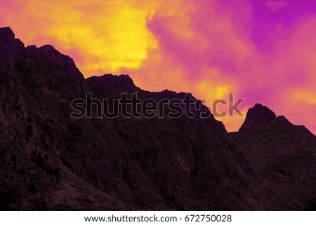 Mountain top outlined with cloudy sunset sky. Pink yellow  sunset. Beautiful nature Norway. Lofoten islands. Reine