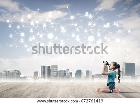 Cute kid girl sitting on wooden floor and looking in binoculars