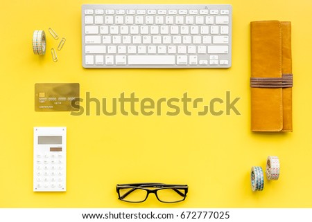 Manager workplace in office with keyboard, calc and bank card on yellow table background top view copyspace