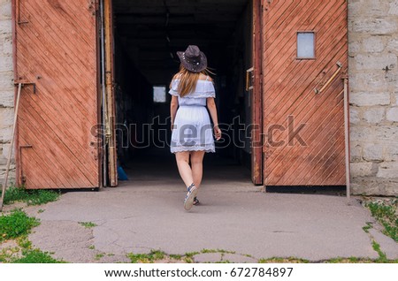 A girl in a white dress and a cowboy hat dancing against the backdrop of a horse at the ranch