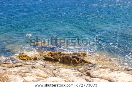 Mighty rock, collapses in a blue sea, with sun glare, majestic rocks