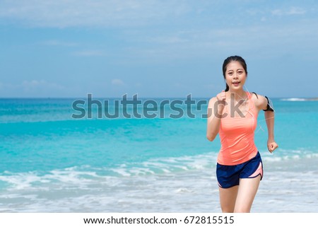smiling pretty girl wearing headphones listening music relaxing and running on beach.