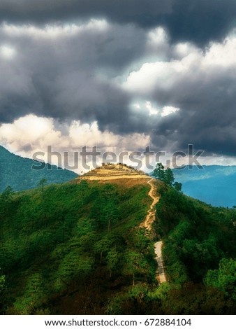 Soft focus of small hilltop village in dark blue stormy cloudy sky 