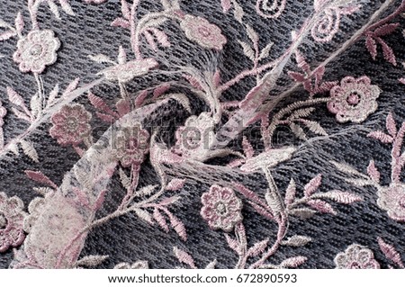 Texture, background, pattern. Pink lace decorated with flowers on a black background. Lace decorated with a pattern and decorative rose on a black background.
