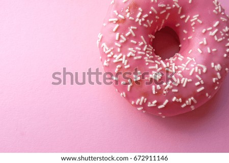 Bitten strawberry donut with colorful sprinkles. Top view.
