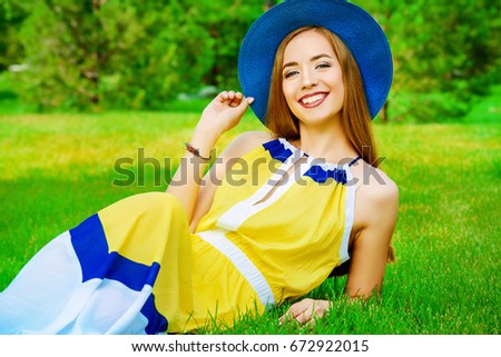 Carefree summer day. Pretty young woman having a rest on a green lawn in a summer park. Beauty, fashion.  