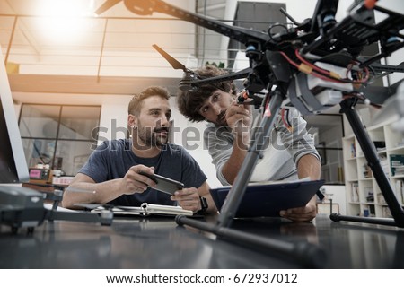 Engineer and technician working together on drone in office Royalty-Free Stock Photo #672937012