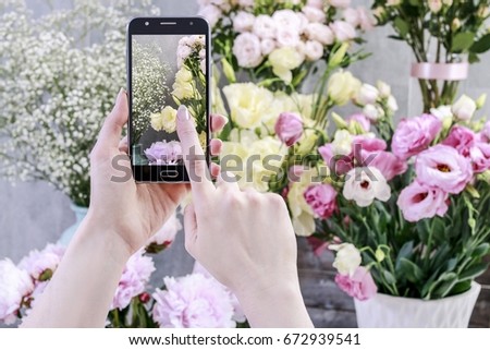 Flowers ordered online. Woman taking picture of plants by her smartpnone. 