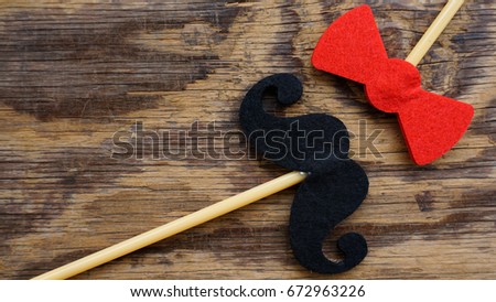 Top or flat lay view of Photo booth props a black mustache and a red bow tie on a wooden background flat lay. Birthday parties and weddings.