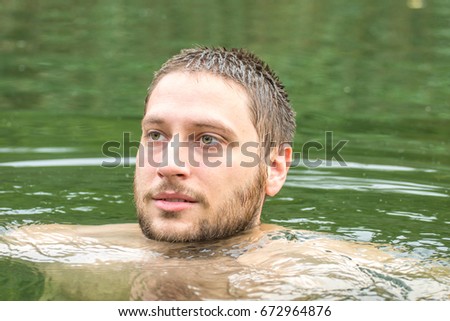 Young man enjoying summer day by the water, swimming