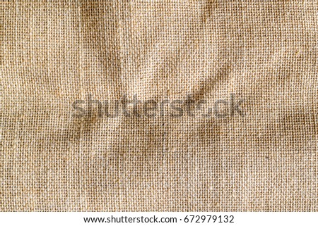 Top view of wrinkle on natural brown hessian sack cloth or gunny sack. Sackcloth is an inexpensive bag made of hessian or burlap formed of jute, coarsely woven fabric. Abstract texture background.