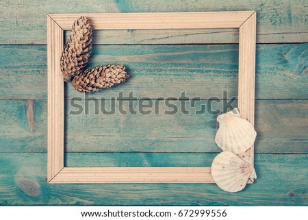 Photo frame with two pine cones and sea shells on old wooden background