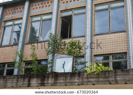 Mystical picture of old stopped broken street clock on facade of destroyed administrative building of factory of the times of USSR. Old broken broken clock tower. Mystic symbolism of destruction