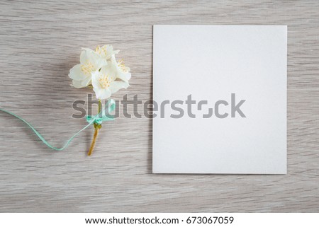 White jasmine with blank greeting card on the wooden background. Fresh, fragrant flowers. 