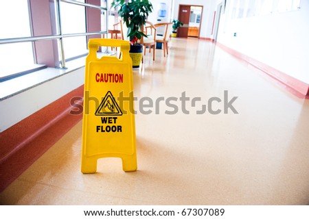 freshly mopped hallway with a caution sign in English.