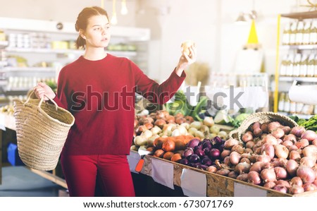 Portrait of young female customer selecting onion in grocery 
