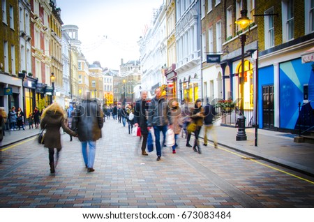 Shoppers walk down busy central London High Street  Royalty-Free Stock Photo #673083484