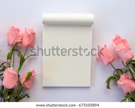 Flat lay with notepad and roses on white background. Romantic banner template with text place. Wedding backdrop with roses and blank white page notepad. Gentle pink flowers on white table top view